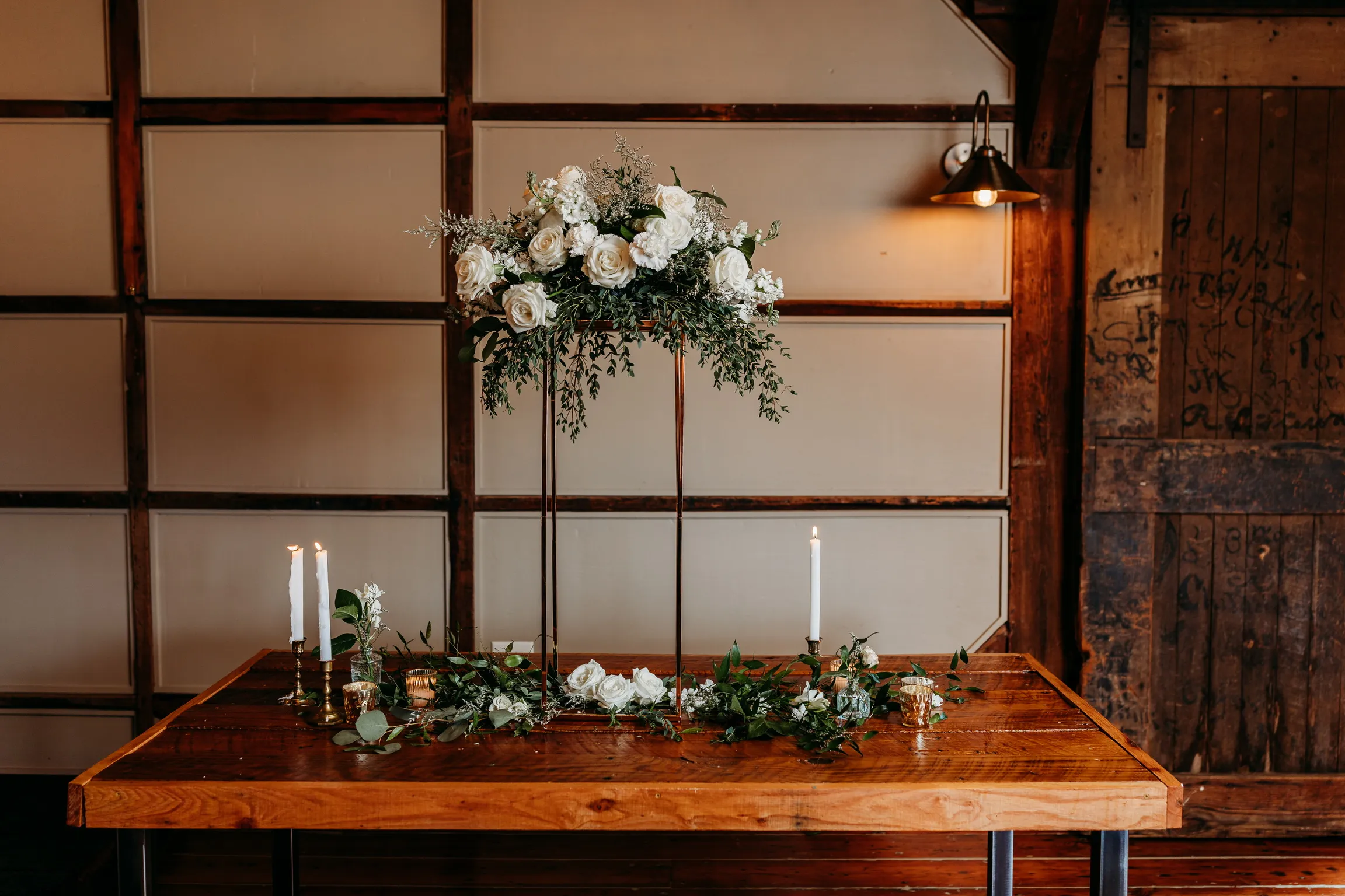 Elevated white floral centerpiece with candles on a reception table
