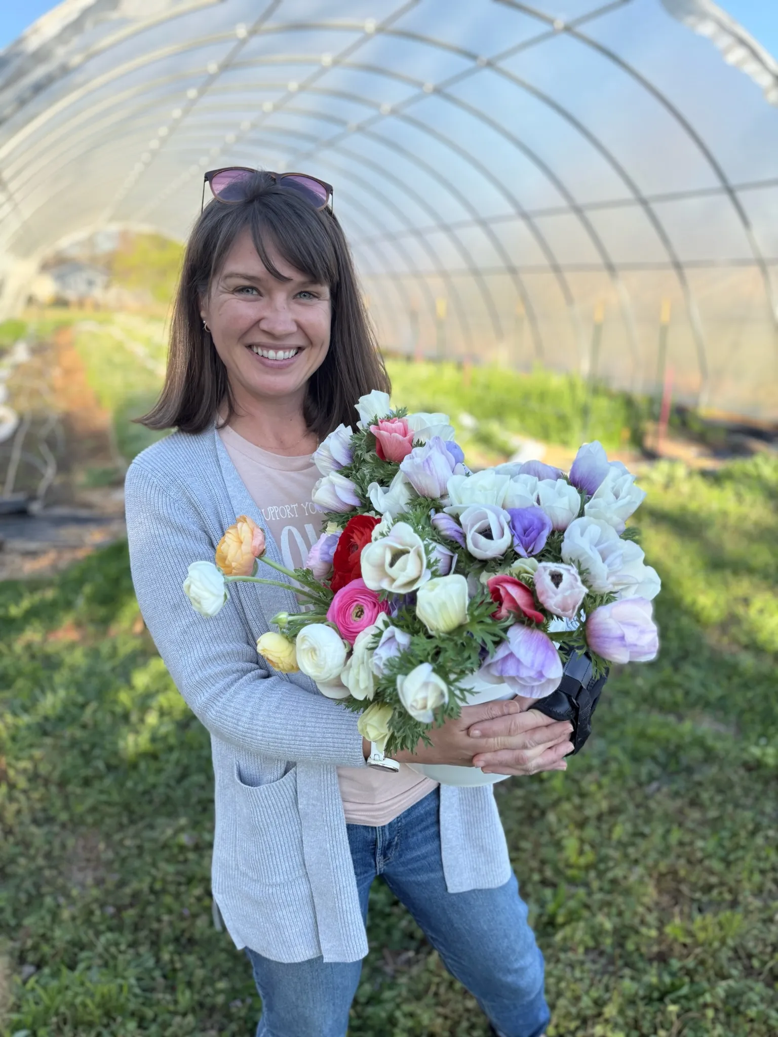 Heather Headley, owner of Heather Florals, holding flowers in her greenhouse